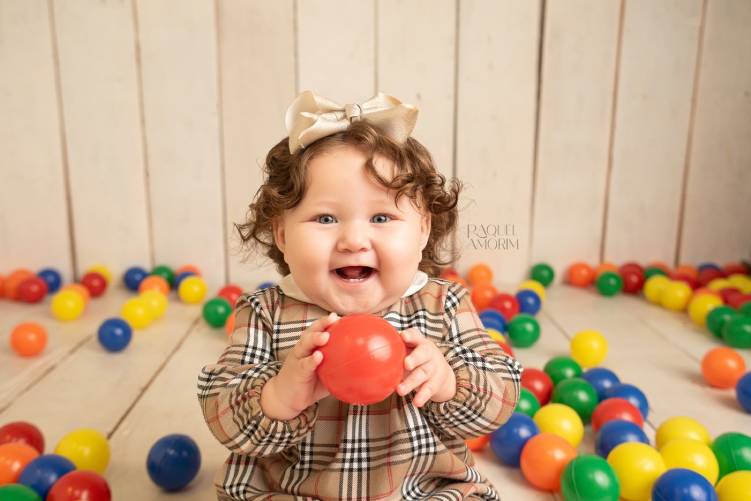 Hadassa, 8 meses, rindo com uma bolinha vermelha na mão